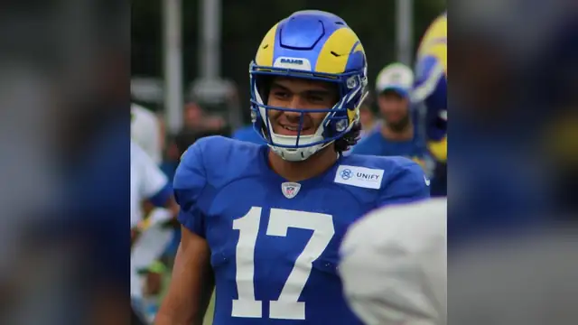 Puka Nacua smiling in his Rams helmet and blue No. 17 practice jersey at training camp