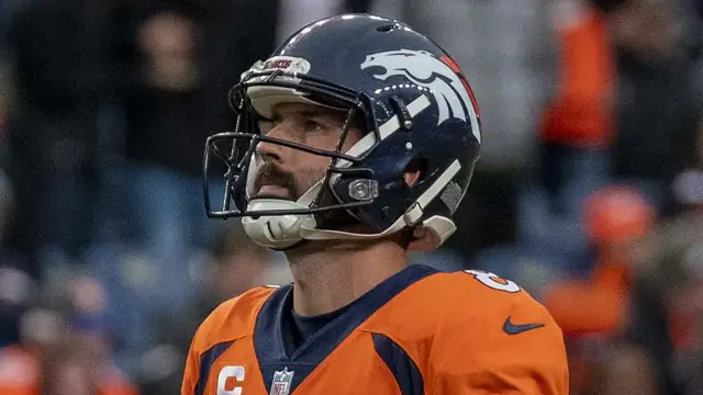 Kicker Brandon McManus in a Denver Broncos helmet and orange No. 8 jersey looks up the field during a 2021 home game