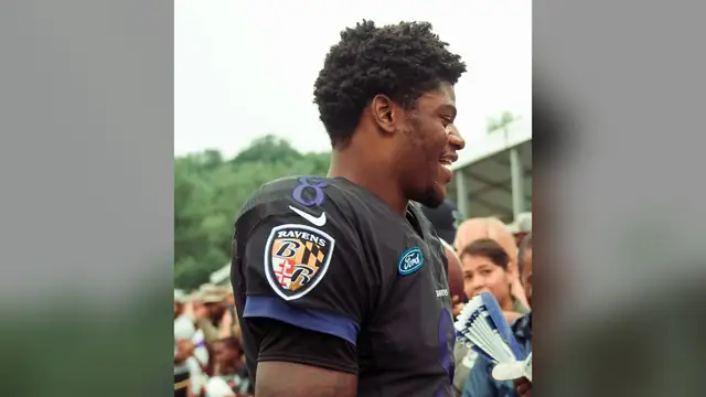 Lamar Jackson in a black Ravens jersey at a training camp practice