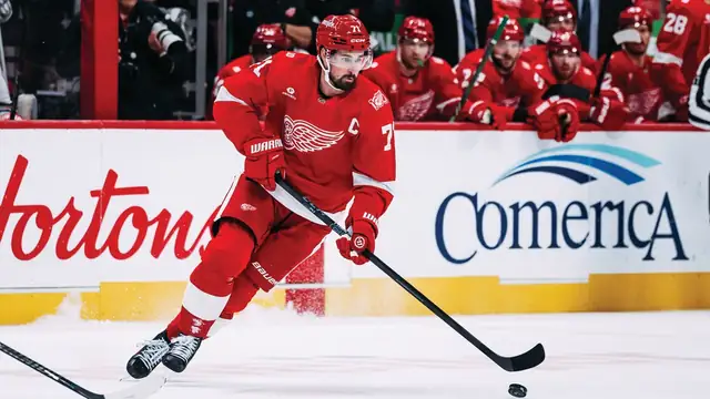 Dylan Larkin skating with the puck in a red Detroit Red Wings jersey
