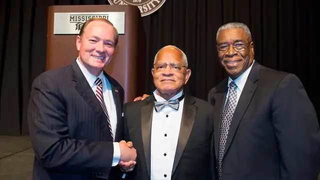 Dr. Richard E. Holmes in a tuxedo and bow tie stands between Mississippi State President Mark Keenum and Dr. Dolphus Weary