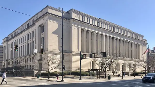 The pale stone Hamilton County Courthouse with its row of tall columns fills a sunny street corner in downtown Cincinnati