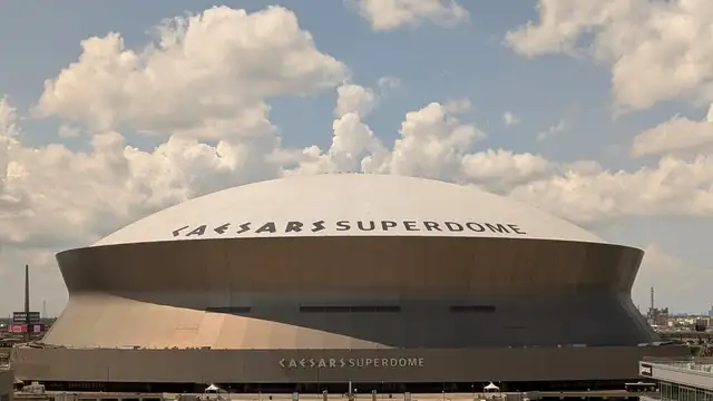 The Caesars Superdome rises above downtown New Orleans under a clear blue sky