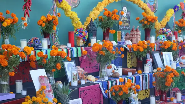 A Day of the Dead altar covered in orange marigolds and candles and photos at a San Antonio mission