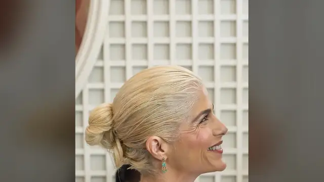 Selma Blair smiling in profile with a green drop earring at the White House