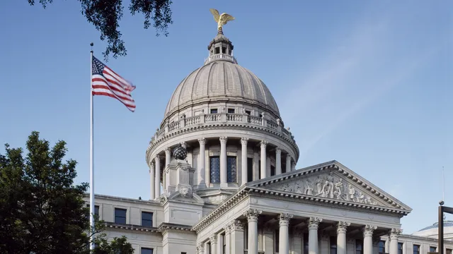The domed Mississippi State Capitol in Jackson with a gold eagle on top and an American flag flying beside its columned front