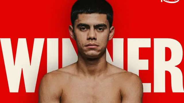 Sergio Mendoza poses with his arms crossed against a red background