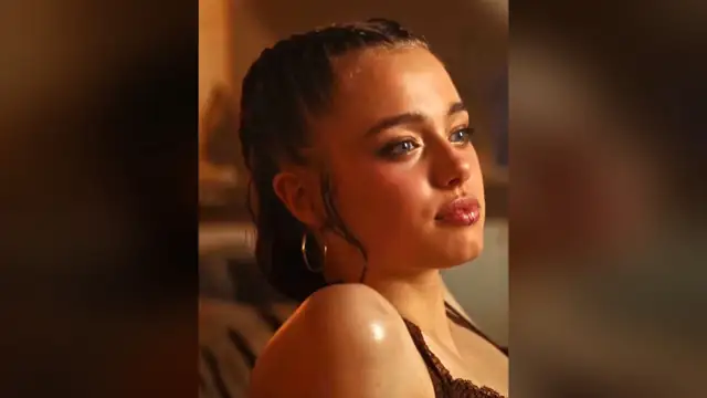 Shiloh Jolie with slicked-back hair and hoop earrings glancing to the side