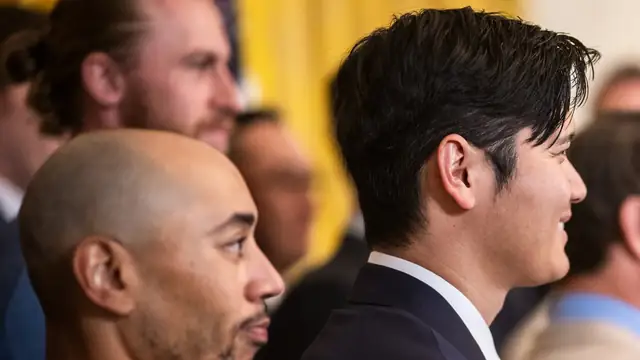 Shohei Ohtani in a dark suit beside teammate Mookie Betts at a Dodgers celebration in Washington
