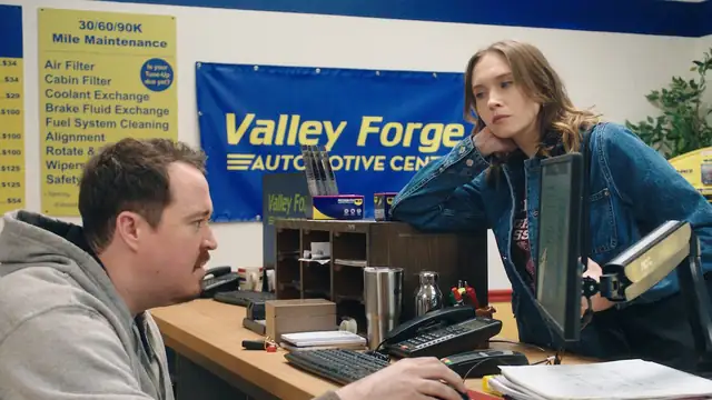 Shane Gillis at a shop counter computer in a still from the Netflix series Tires