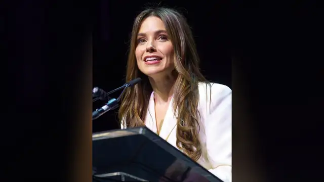 Sophia Bush in a white blazer speaking at a podium at SXSW 2024