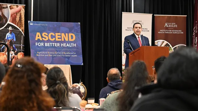 Rep. Henry Cuellar speaks at a podium to a seated audience at a community event in Laredo, Texas