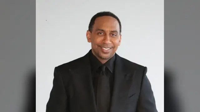 Stephen A. Smith smiling in a black suit and shirt