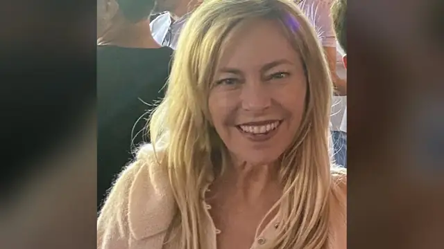 Sutton Stracke smiling in a pink sweater at a crowded West Hollywood bar