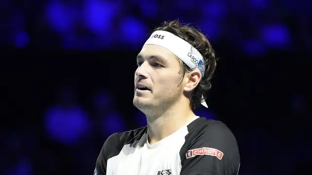 American tennis player Taylor Fritz in a white headband and black and white shirt during an indoor match