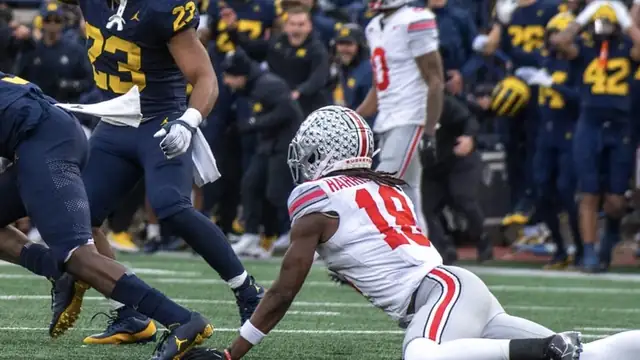 Marvin Harrison Jr. in a white Ohio State uniform braces on the turf during a 2023 college game against Michigan