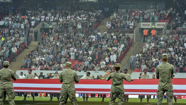 Airmen in camouflage uniforms hold a giant U.S. flag on the field at Wembley Stadium in London before an NFL game in 2014