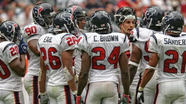Houston Texans players in white jerseys and navy helmets gather in a huddle during a game