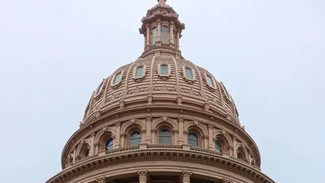 The pink granite dome of the Texas State Capitol in Austin rising against an overcast sky
