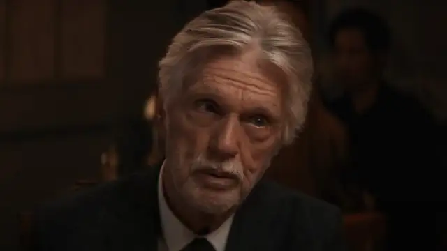 Tom Skerritt with silver hair in a dark suit during a dinner scene from East of the Mountains