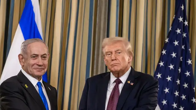 Benjamin Netanyahu and President Donald Trump clasping hands in front of Israeli and American flags