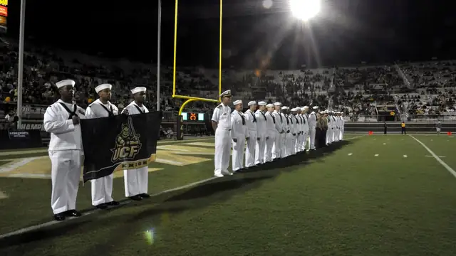 Sailors standing in a line on the field under the stadium lights during a UCF Knights home football game in Orlando