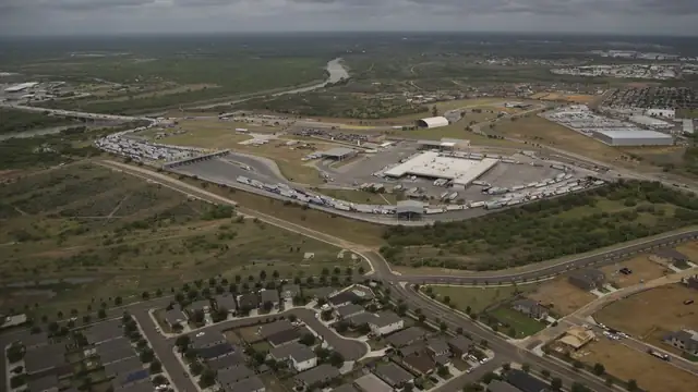 Aerial view of commercial trucks lined up at the World Trade Crossing bridge between Laredo Texas and Mexico beside the Rio Grande