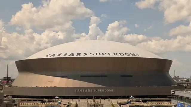 The domed roof of the Caesars Superdome in New Orleans under a partly cloudy sky