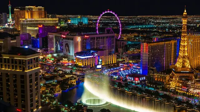 Nighttime view of the Las Vegas Strip with illuminated hotels and the Bellagio fountains in the foreground