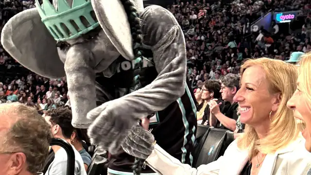 WNBA Commissioner Cathy Engelbert laughs with the New York Liberty elephant mascot in the stands at a packed arena