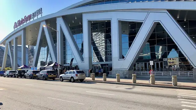 The curved white steel frame and glass front of State Farm Arena in downtown Atlanta on a sunny day