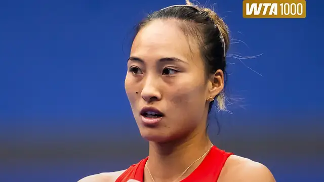 Zheng Qinwen in a red top looks ahead against a blue background