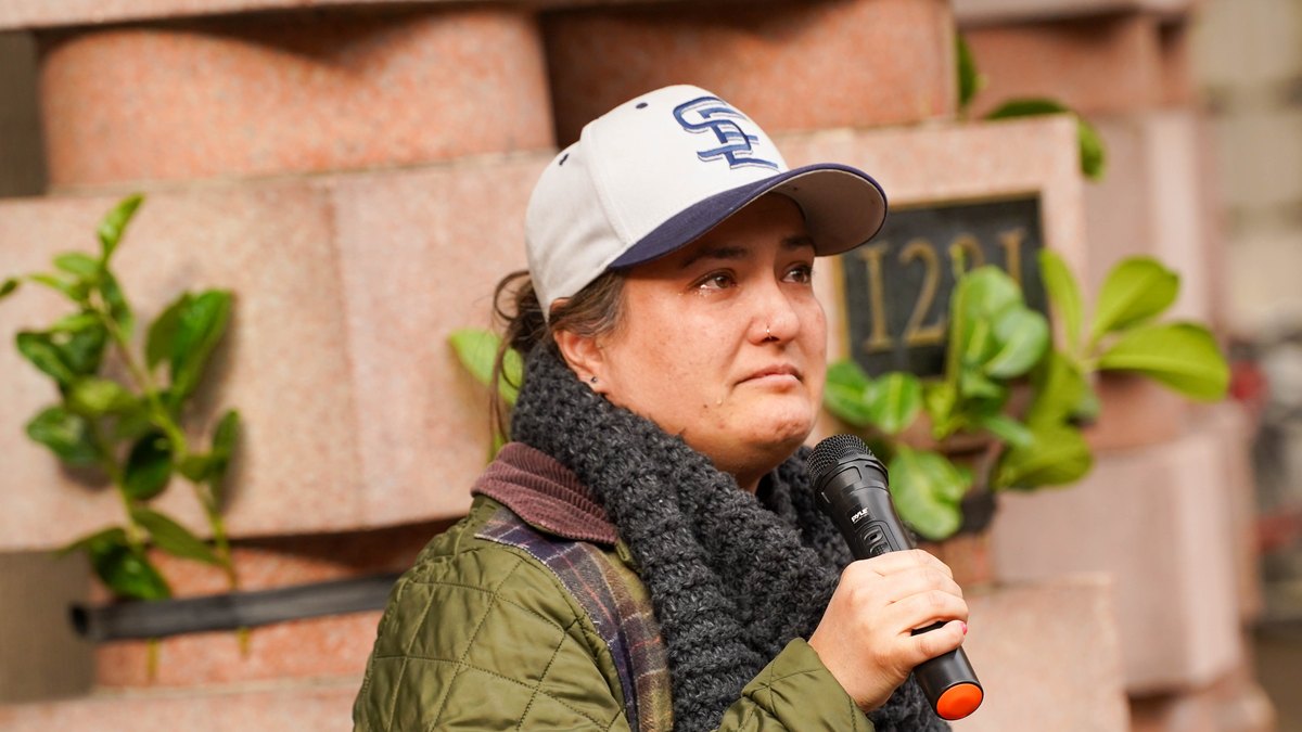 Portland City Councilor Tiffany Koyama Lane speaking into a microphone at an outdoor community event