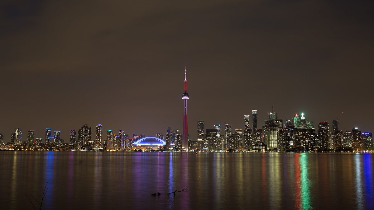 The Toronto skyline and CN Tower lit up at night over Lake Ontario
