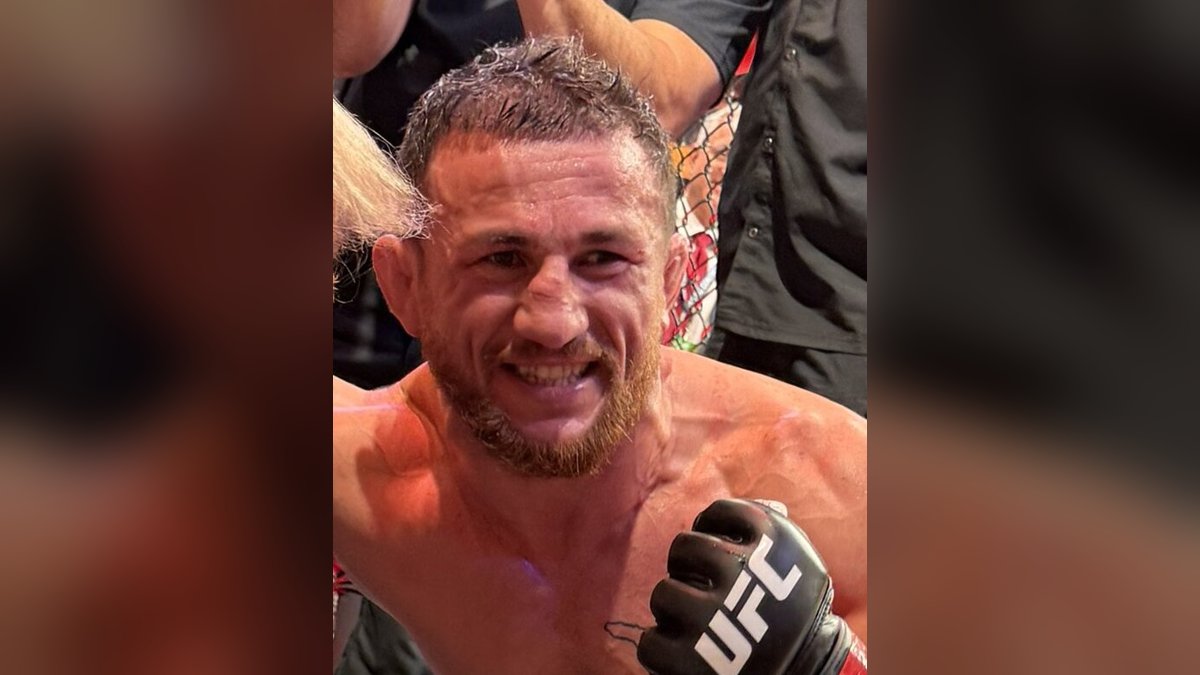 Merab Dvalishvili smiling with his UFC glove raised inside the octagon after a fight