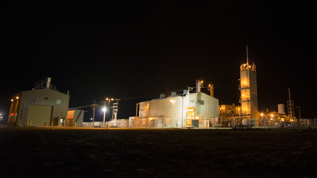The federal helium plant near Amarillo, Texas lit up at night with its tall processing tower and white buildings glowing under a black sky