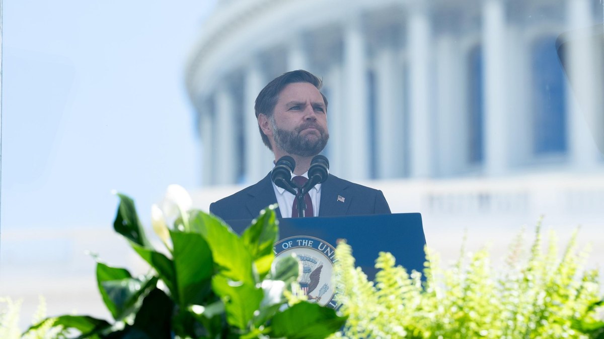 Vice President JD Vance in a dark suit speaks at a podium with the vice presidential seal in front of the U.S. Capitol dome