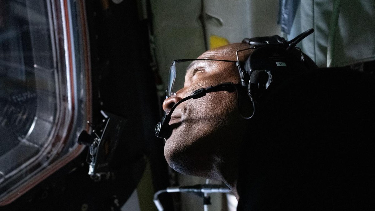 NASA astronaut Victor Glover looking out an Orion capsule window during the Artemis II flight around the moon