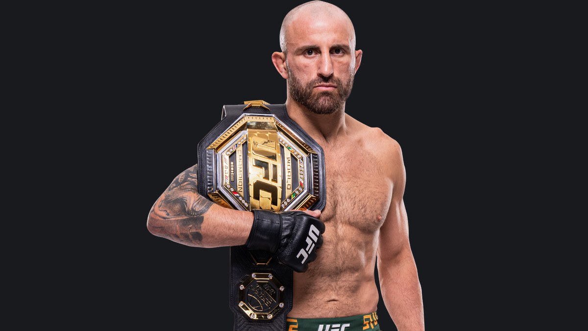 Alex Volkanovski in green UFC fight shorts holds the featherweight title belt on his shoulder