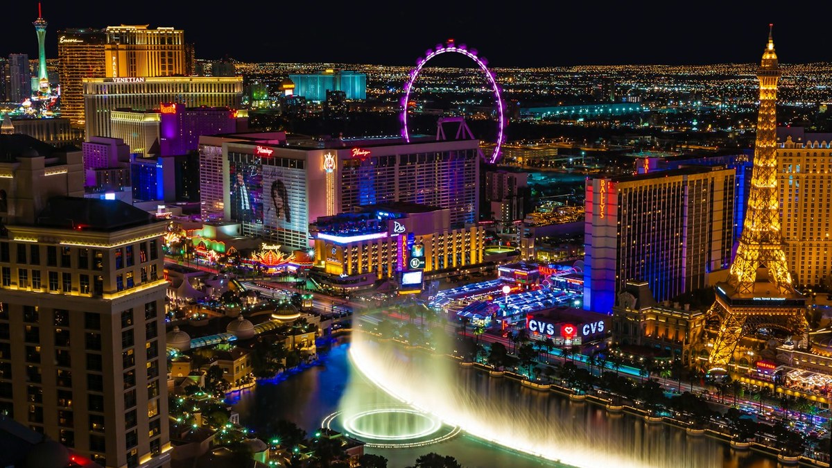 Nighttime view of the Las Vegas Strip with illuminated hotels and the Bellagio fountains in the foreground