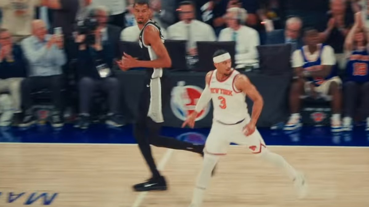 Victor Wembanyama in his black Spurs uniform runs up the court beside Josh Hart of the Knicks during the 2026 NBA Finals