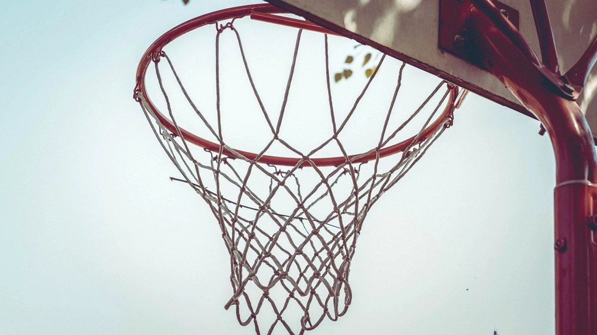 A close-up of an outdoor basketball hoop with a red rim and white net