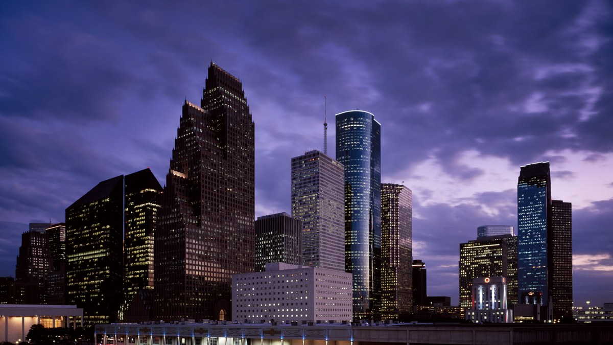 The downtown Houston skyline glowing at twilight under a purple sky